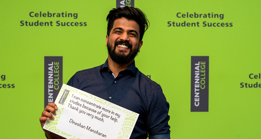 Picture of Dineshan Manoharan smiling while holding up a sign that says I can concentrate more in my studies because of your help, thank you very much